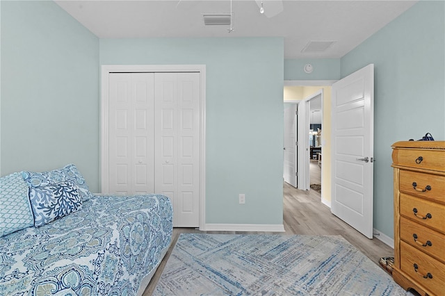 bedroom with ceiling fan, a closet, and light hardwood / wood-style floors