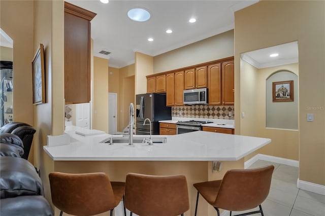 kitchen featuring tasteful backsplash, kitchen peninsula, a kitchen bar, stainless steel appliances, and light tile patterned floors