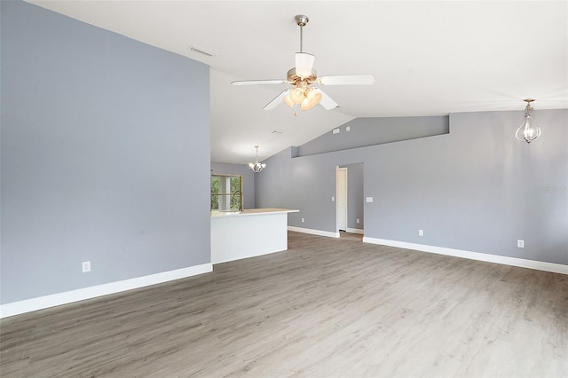 unfurnished living room with ceiling fan with notable chandelier, lofted ceiling, and dark wood-type flooring