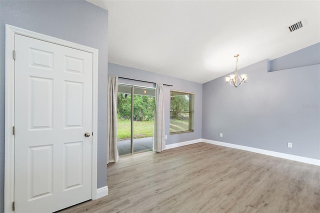 unfurnished room with a notable chandelier, vaulted ceiling, and light hardwood / wood-style floors