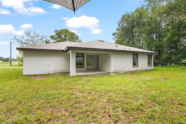 back of property with a lawn and a patio area