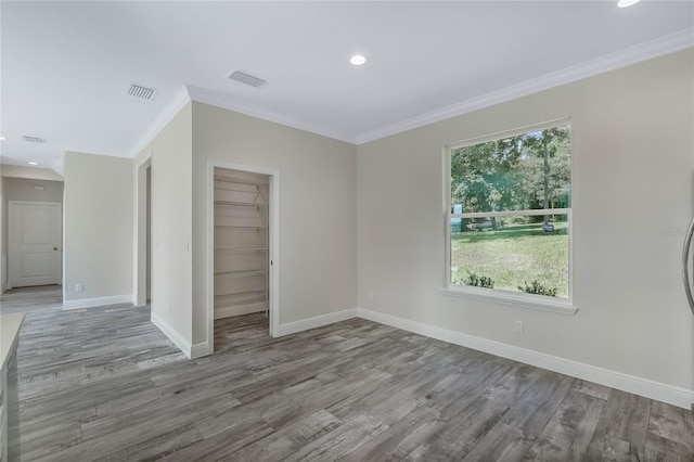 empty room with ornamental molding and light hardwood / wood-style floors