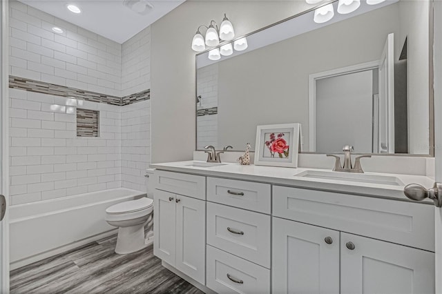 full bathroom with vanity, toilet, wood-type flooring, and tiled shower / bath