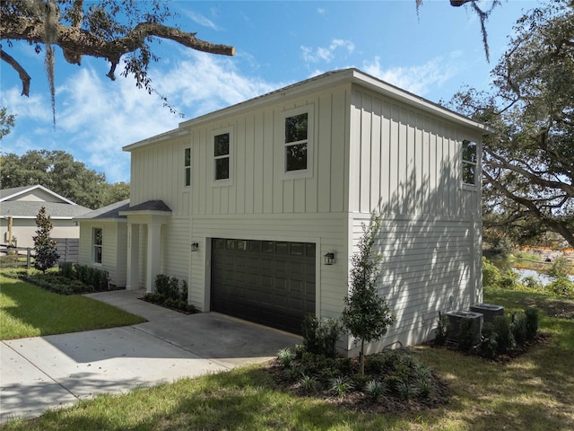 front of property featuring a front yard, central AC unit, and a garage