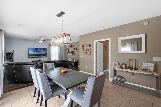 tiled dining room with ceiling fan with notable chandelier