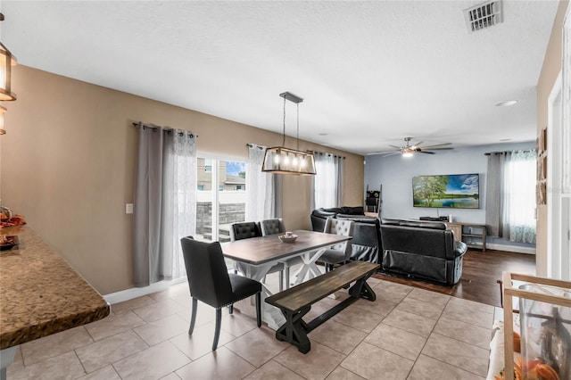 dining area with a textured ceiling, ceiling fan with notable chandelier, and light tile patterned floors