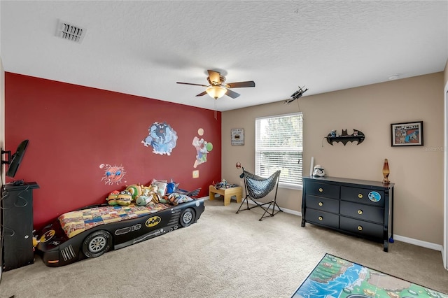 carpeted bedroom featuring ceiling fan and a textured ceiling