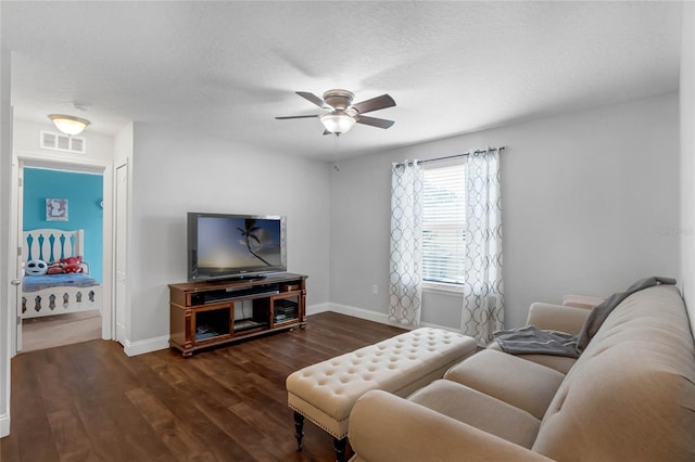 living room with ceiling fan, a textured ceiling, and dark wood-type flooring