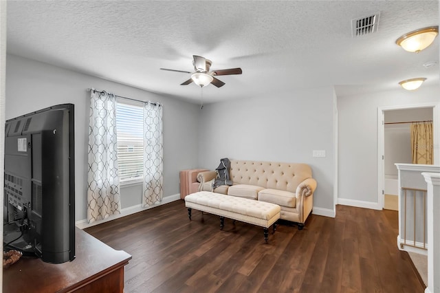 living room with a textured ceiling, dark hardwood / wood-style flooring, and ceiling fan