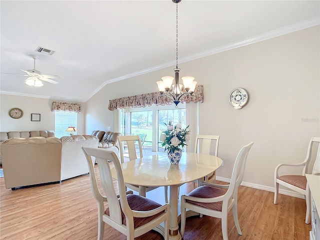 dining area with ceiling fan with notable chandelier, ornamental molding, vaulted ceiling, and light wood-type flooring