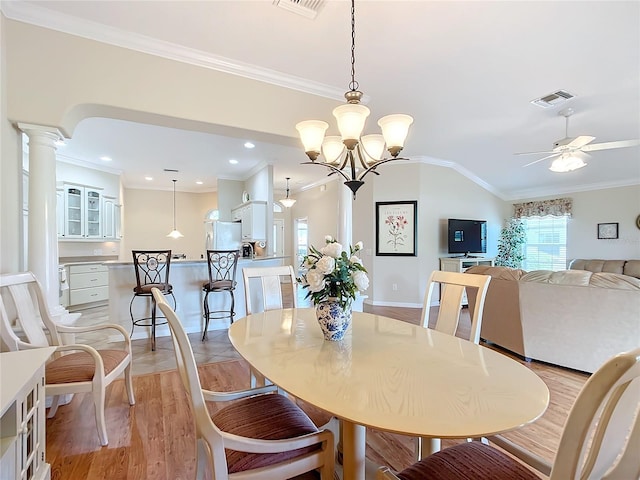 dining room with crown molding, light hardwood / wood-style flooring, ceiling fan, vaulted ceiling, and ornate columns