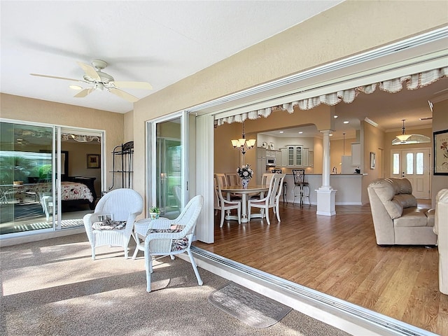 sunroom with ceiling fan with notable chandelier and decorative columns