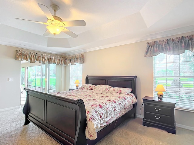 carpeted bedroom with multiple windows, access to outside, a raised ceiling, and ceiling fan