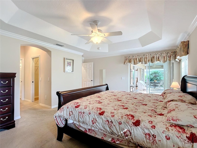 carpeted bedroom featuring ceiling fan, ornamental molding, a tray ceiling, and access to exterior