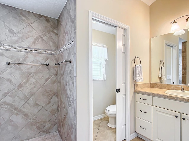 bathroom featuring a tile shower, vanity, tile patterned floors, and toilet