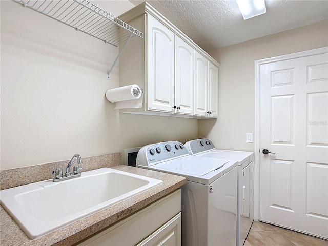 laundry area featuring light tile patterned flooring, washer and dryer, sink, cabinets, and a textured ceiling