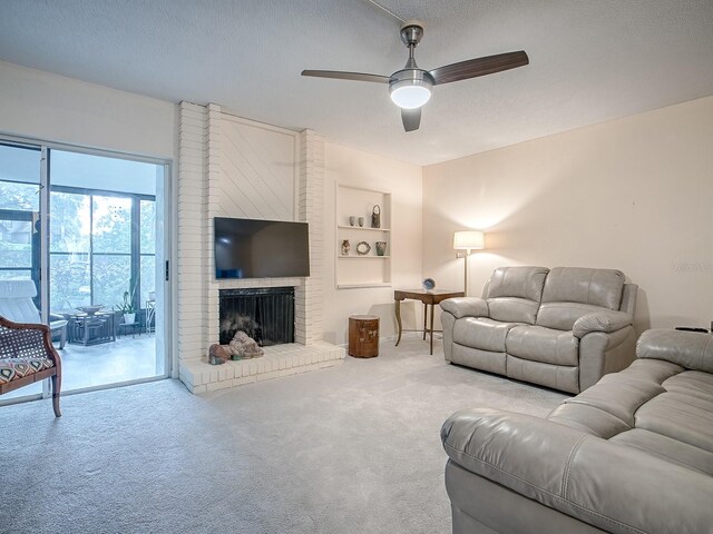 carpeted living room with ceiling fan, a textured ceiling, a fireplace, and built in shelves