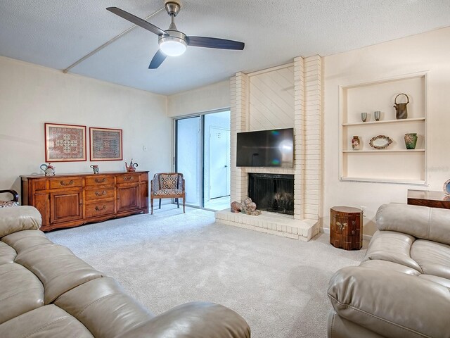 carpeted living room with a textured ceiling, a fireplace, and ceiling fan