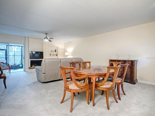 carpeted dining area featuring ceiling fan, a textured ceiling, and a brick fireplace