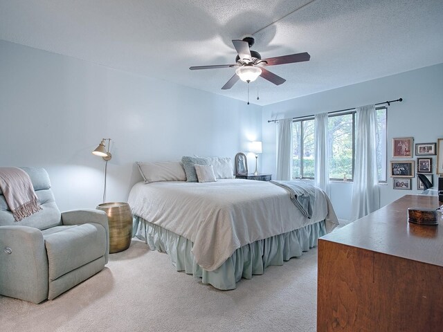 carpeted bedroom with ceiling fan and a textured ceiling