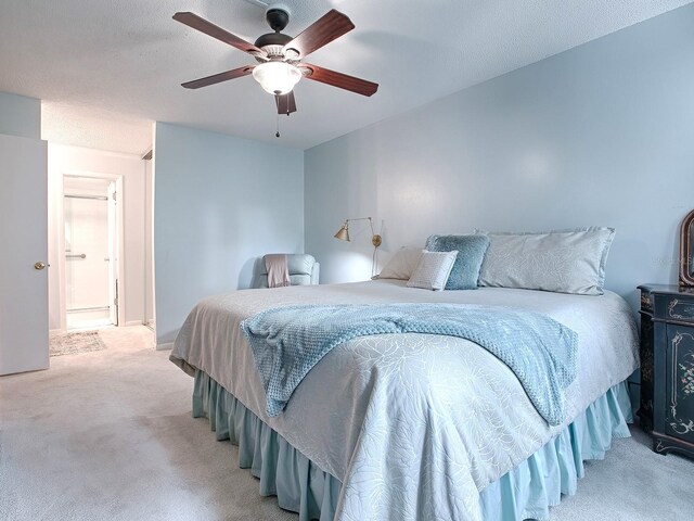 bedroom with a textured ceiling, light colored carpet, and ceiling fan