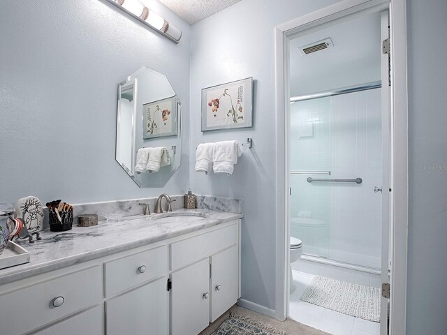 bathroom with a shower with door, vanity, a textured ceiling, and toilet