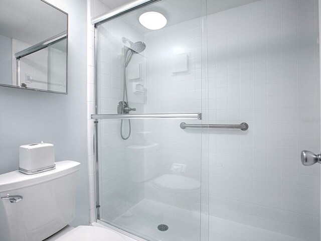 bathroom featuring toilet and a shower with shower door