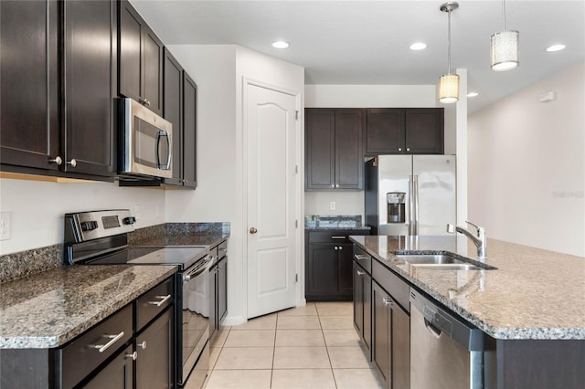 kitchen with light tile patterned floors, a sink, appliances with stainless steel finishes, an island with sink, and pendant lighting