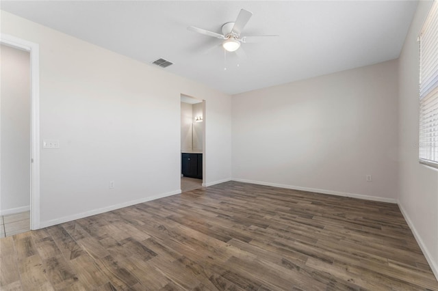 unfurnished room featuring a ceiling fan, visible vents, baseboards, and wood finished floors