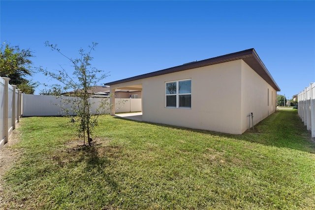 rear view of house with a lawn, a fenced backyard, and stucco siding