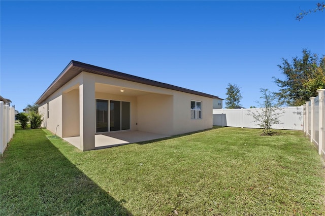 back of house featuring a yard, a fenced backyard, a patio area, and stucco siding