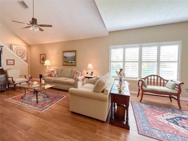 living room with wood-type flooring, a textured ceiling, vaulted ceiling, and ceiling fan