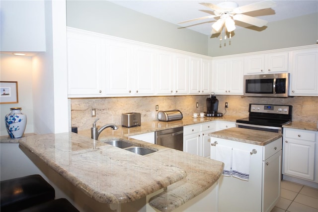 kitchen featuring sink, kitchen peninsula, white cabinetry, appliances with stainless steel finishes, and a kitchen bar