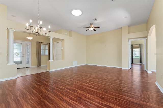 empty room featuring a wealth of natural light, hardwood / wood-style flooring, and ceiling fan with notable chandelier