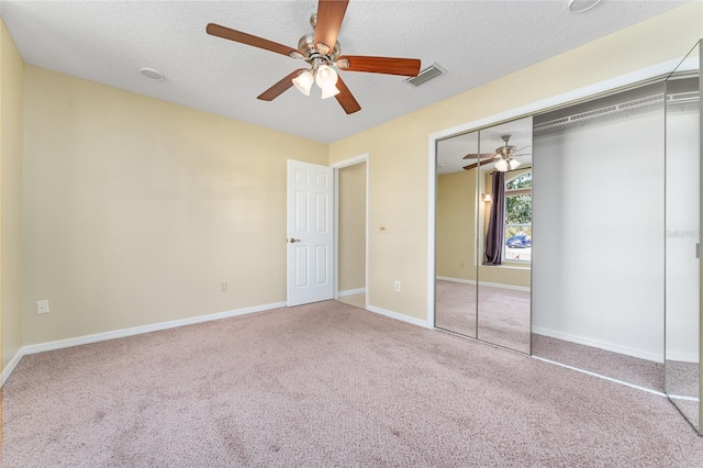 unfurnished bedroom featuring a closet, ceiling fan, carpet flooring, and a textured ceiling