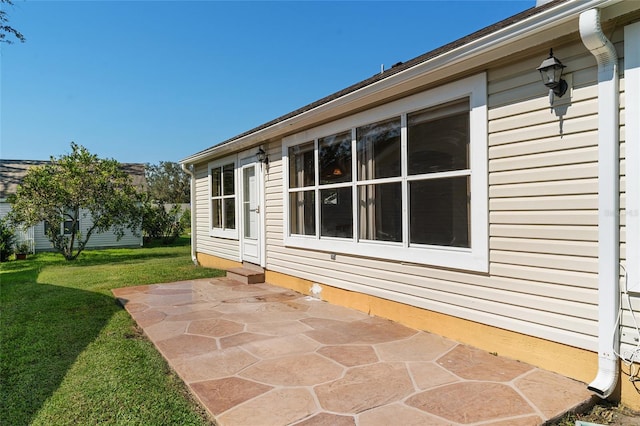 view of side of property featuring a patio and a lawn