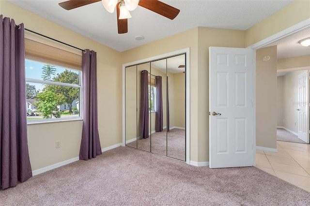 unfurnished bedroom featuring light carpet, a closet, and ceiling fan