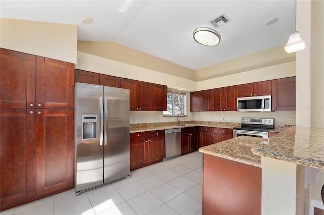 kitchen with kitchen peninsula, lofted ceiling, light stone counters, pendant lighting, and stainless steel appliances