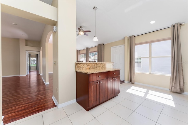 kitchen with light hardwood / wood-style floors, light stone countertops, decorative light fixtures, and plenty of natural light