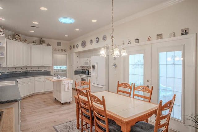 dining space featuring crown molding, light hardwood / wood-style floors, and a chandelier