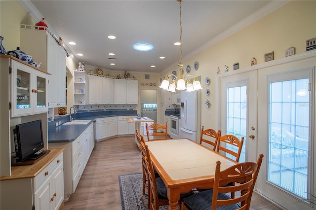 kitchen with white appliances, crown molding, white cabinetry, light hardwood / wood-style flooring, and decorative light fixtures