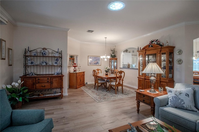 living room with crown molding, a chandelier, and light wood-type flooring