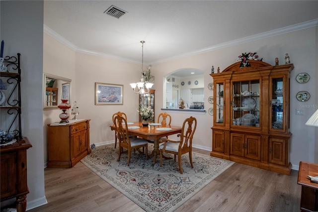 dining area featuring crown molding, a notable chandelier, and light wood-type flooring