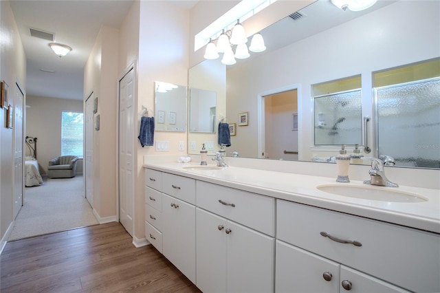 bathroom with a shower with shower door, vanity, and wood-type flooring