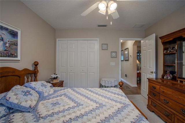 bedroom featuring a closet, light colored carpet, a textured ceiling, and ceiling fan