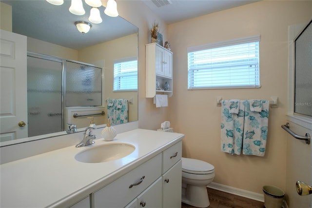 bathroom with wood-type flooring, vanity, a wealth of natural light, and toilet