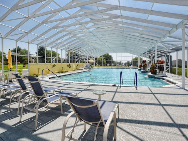 view of pool with glass enclosure and a patio