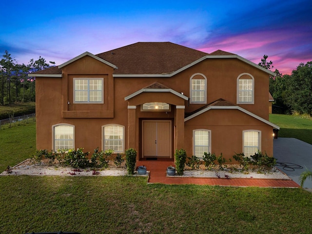 view of front of property with a front yard, roof with shingles, and stucco siding