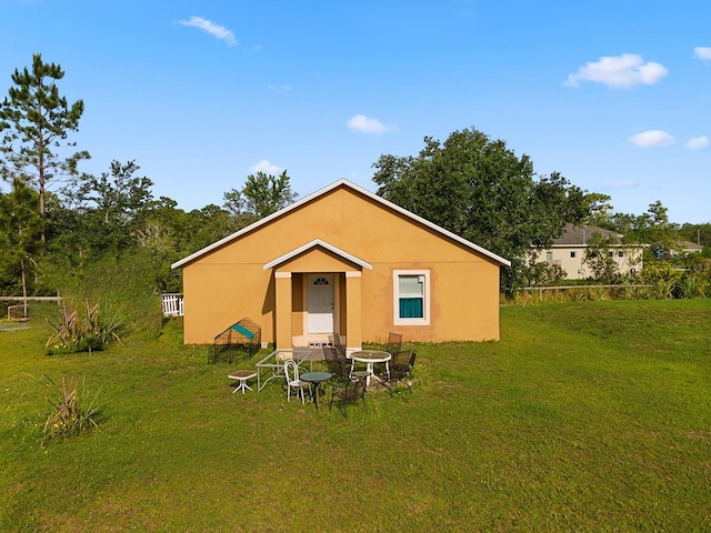 back of property featuring a lawn and stucco siding