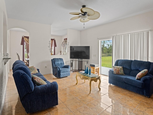 living area with arched walkways, light tile patterned flooring, and a ceiling fan